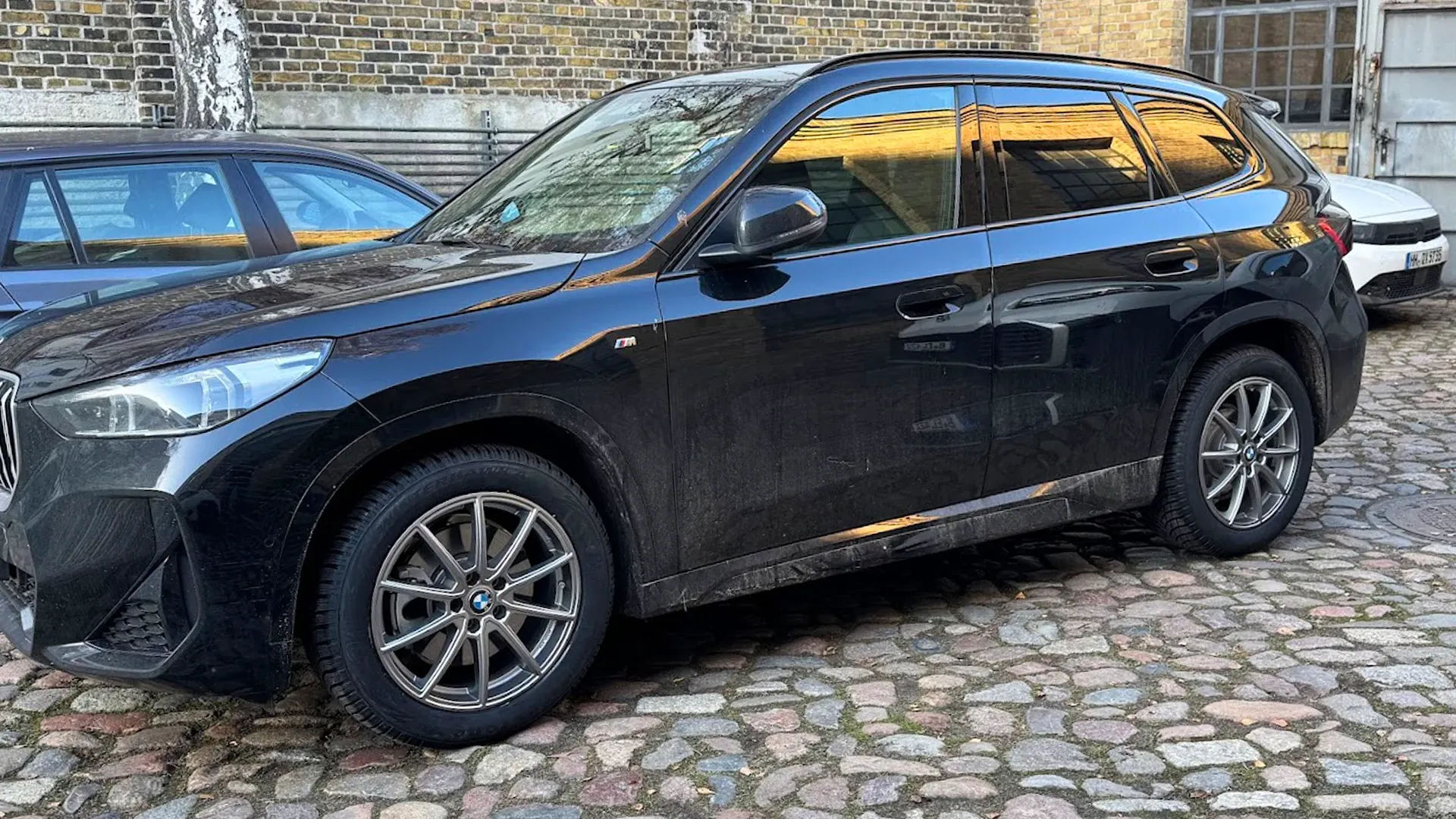Schwarzer BMW SUV auf Kopfsteinpflaster vor der Werkstatt