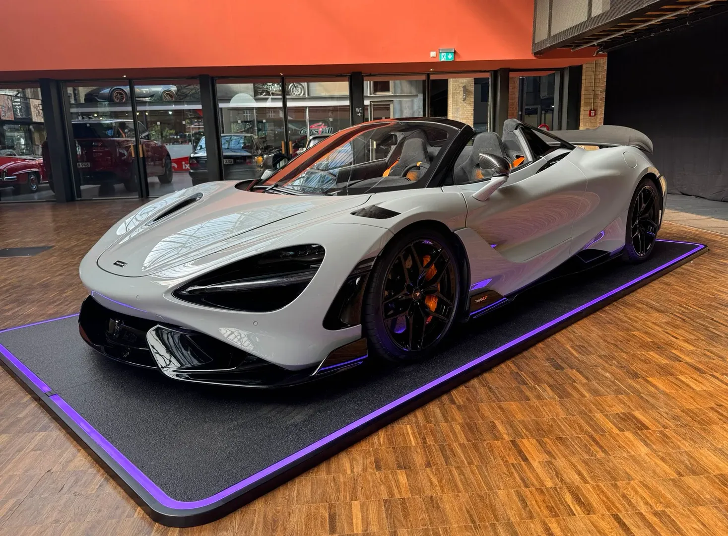 Weißer McLaren 765LT Spider auf violettem Podest im Showroom