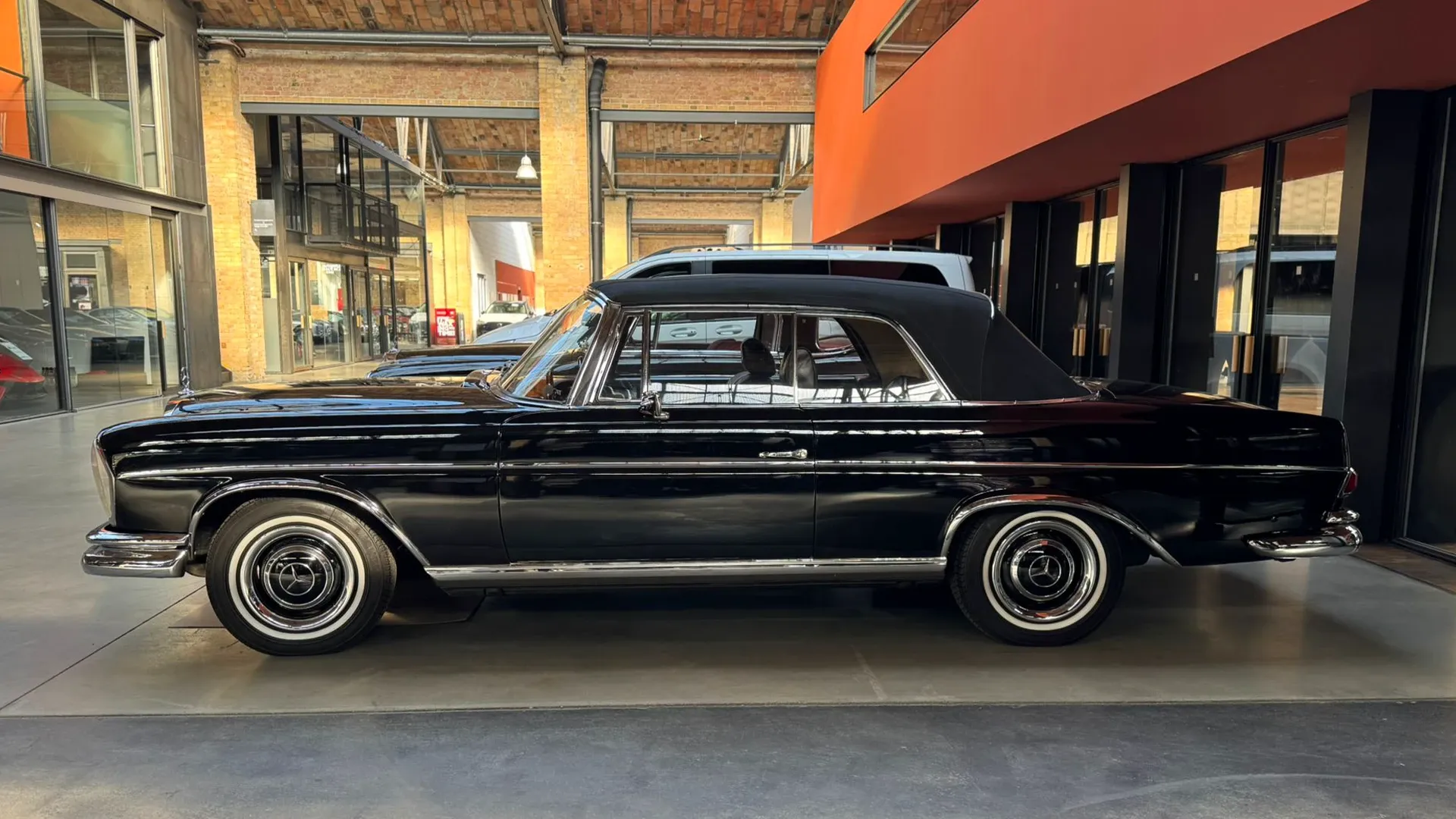 Schwarzes Mercedes-Benz W111 Coupé im Showroom der Classic Remise