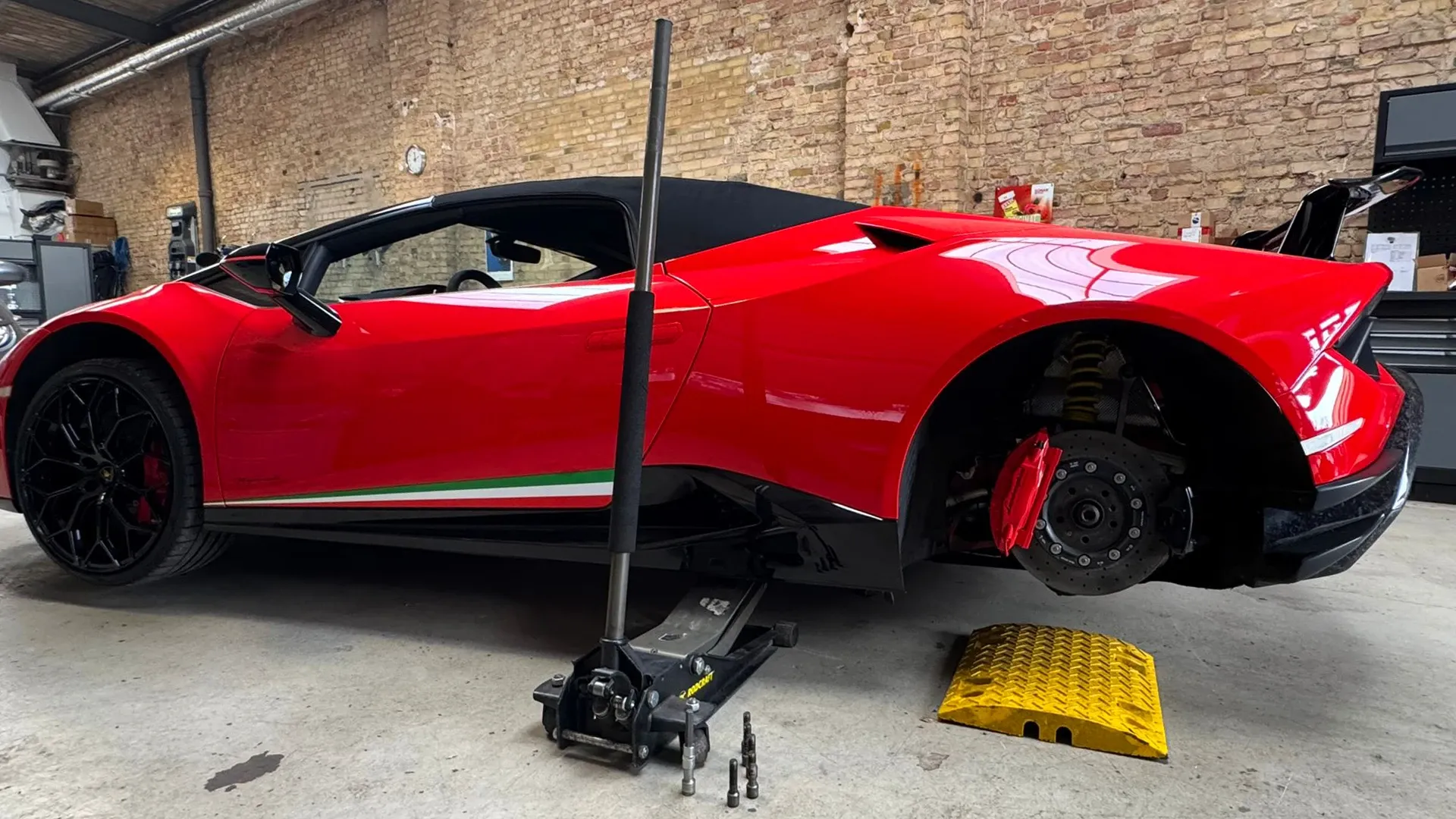 Roter Lamborghini auf dem Wagenheber mit abgenommenem Rad in der Werkstatt