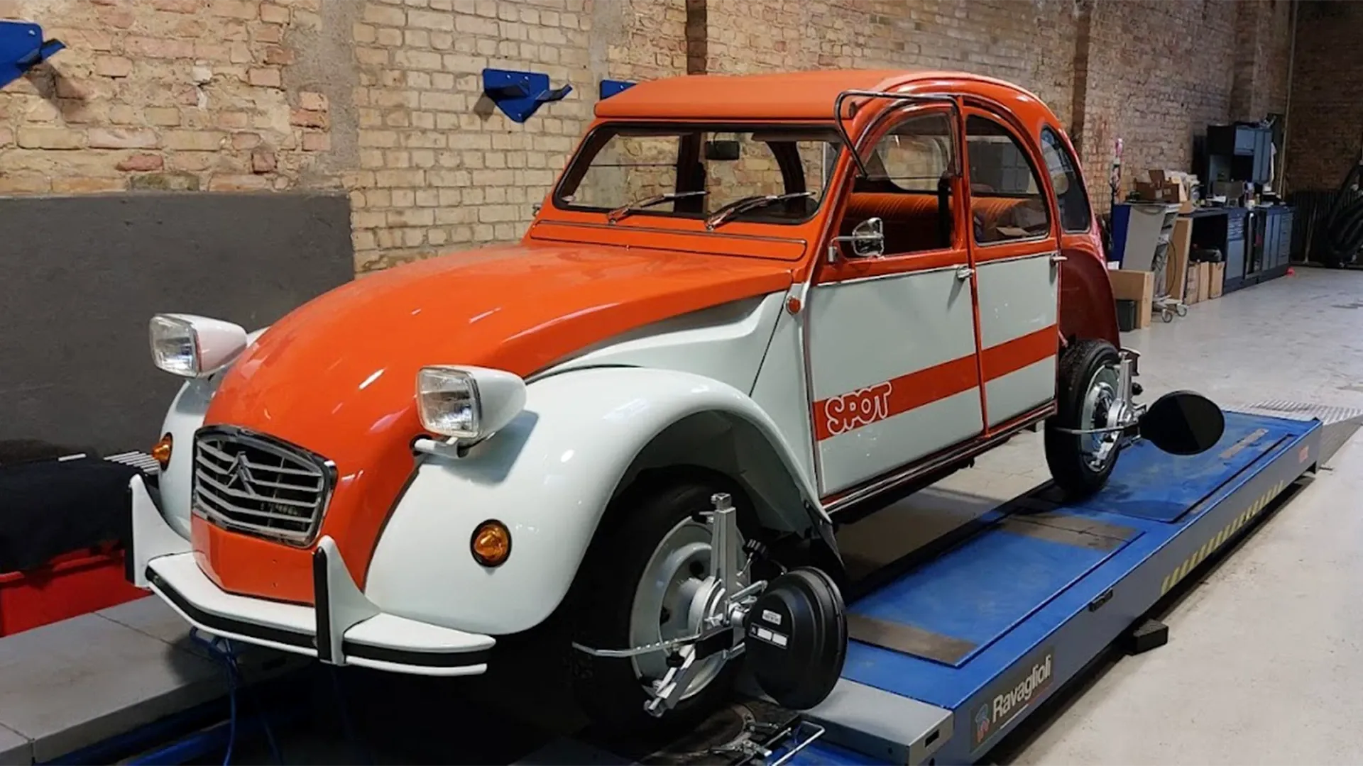 Orange-weißer Citroën 2CV auf der Hebebühne in der Werkstatt